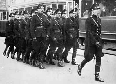 810759 Afbeelding van een groep marcherende politieagenten op het Stationsplein te Utrecht.